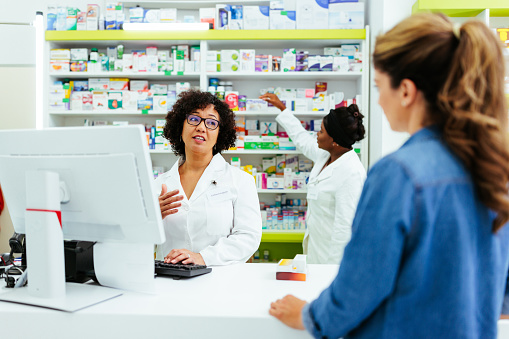 A pharmacist is having a friendly talk with one of the regular customers at the pharmacy