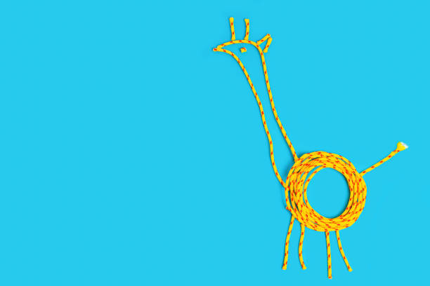 Giraffe shape made from braided cord on blue background with copy space.