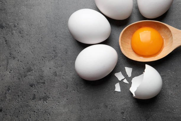 istock Raw chicken eggs and spoon with yolk on grey table, flat lay. Space for text 1405646985