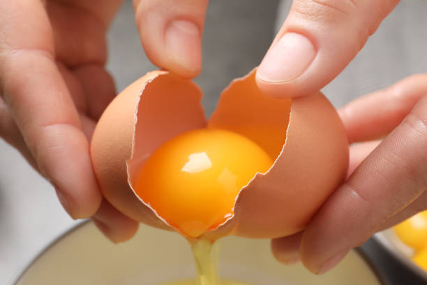 istock Woman separating egg yolk from white over bowl, closeup 1405646987