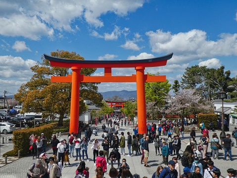 Japan, Kyoto Prefecture, Fushimi Inari  Taisha - April, 2019: Crowd of international visitors at the entrance to Fushimi Inari shinto shrine.