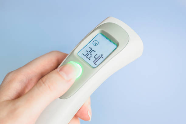 istock Female hand holding a modern infrared thermometer isolated over blue background 1405647408