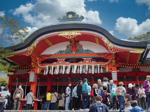 Japan, Kyoto Prefecture, Fushimi Inari  Taisha - April, 2019: Local visitors and tourists visiting brightly coloured worship place at Fushimi Inari shrine complex on a mountain near Kyoto.