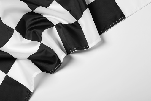 Checkered finish flag on white background, top view. Space for text
