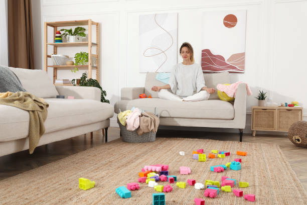 istock Young mother meditating on sofa in messy living room 1405648437