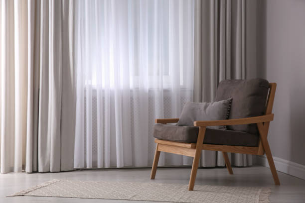 istock Comfortable armchair near window indoors, space for text. Interior design 1405648572