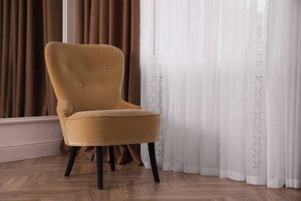 istock Comfortable armchair near window indoors, space for text. Interior design 1405648589