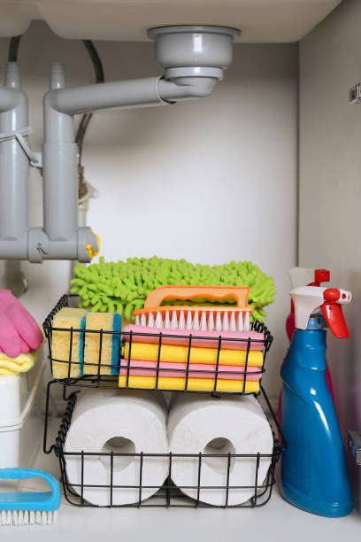 istock Open under sink cabinet with different cleaning supplies in kitchen 1405648594