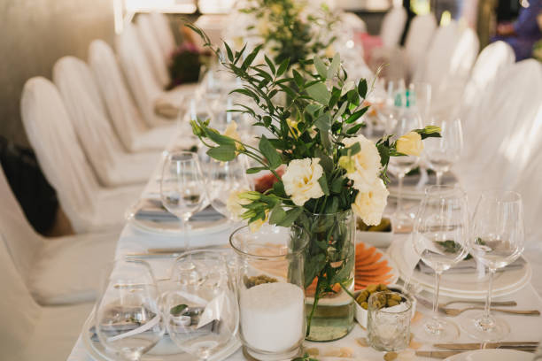 istock Table setting at the wedding reception. Floral compositions with beautiful flowers and greenery, candles, laying and plates on a decorated table. 1405648599