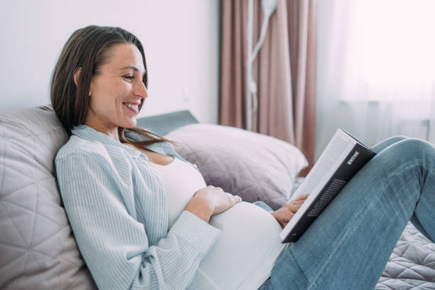 istock Pregnant woman lying in her bed and reading a book. 1405648876