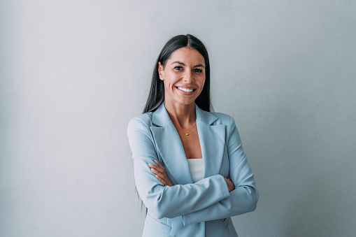 Portrait of a beautiful smiling businesswoman standing with crossed arms in her office and looking at camera.