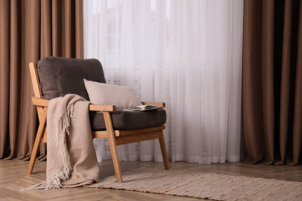 istock Comfortable armchair with blanket near window indoors, space for text. Interior design 1405649622