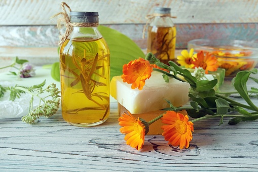 Calendula flowers, soap, oils and tinctures, on a wooden background, natural ingredients, alternative medicine