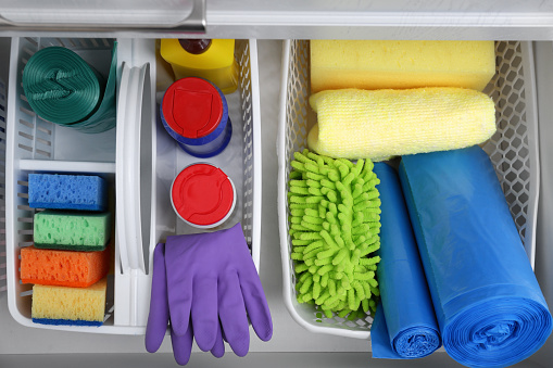 Different cleaning supplies in open drawer, top view