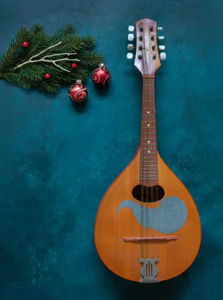 Old mandolin and fir-tree branches with Christmas decor. Christmas and New Year's concept. Top view, close-up on dark concrete background.