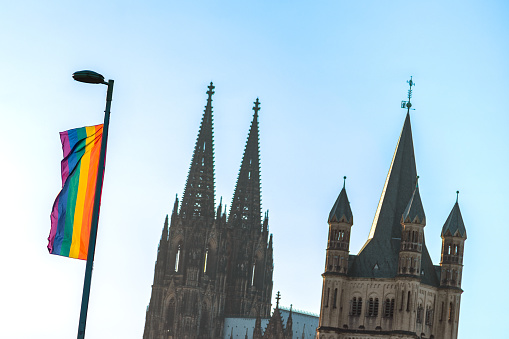 An LGBT flag seen from the Deutz Bridge in Cologne can be seen next to Cologne Cathedral and the church Groß Sankt Martin.