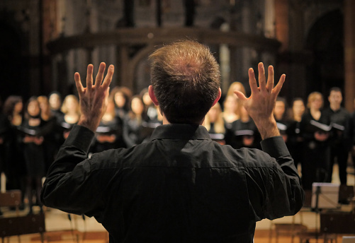Musician leads a choir during a concert in a cathedral.