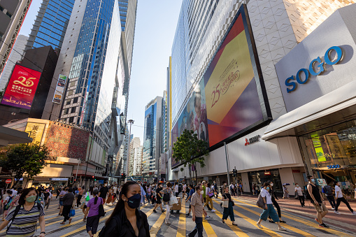 Hong Kong - June 28, 2022 : Pedestrians walk past the electronic screens with a slogan celebrating the 25th anniversary of Hong Kong's handover from Britain to China, in Hennessy Road, Causeway Bay, Hong Kong.