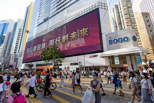 Hong Kong - June 28, 2022 : Pedestrians walk past an electronic screen with a slogan celebrating the 25th anniversary of Hong Kong's handover from Britain to China, in Hennessy Road, Causeway Bay, Hong Kong.