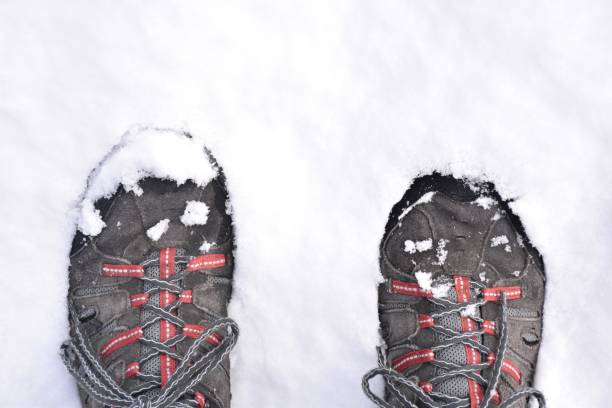 ноги в походных ботинках наступают на снег. - snow track human foot steps стоковые фото и изображения
