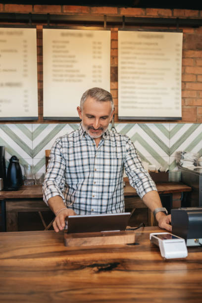 istock Man standing at bar looking at laptop 1405661220