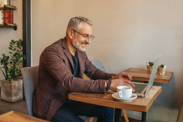 istock Man sitting sideways to camera working on laptop 1405661284