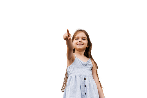 Adorable child girl pointing finger forward on white background with blank space for advert. Creative idea for sale discount for children products