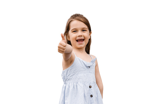 Adorable positive child girl smiling and shows thumbs up on white background in studio. Kids lifestyle and having fun. Lifestyle of happy toddler