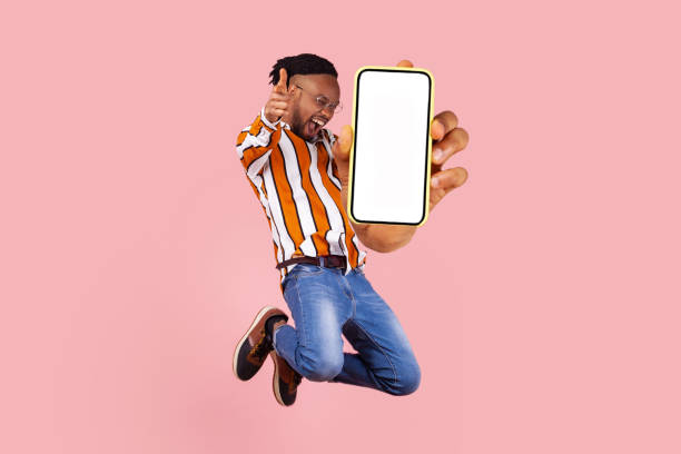 istock Young happy man jumping and showing his mobile phone display. 1405669995