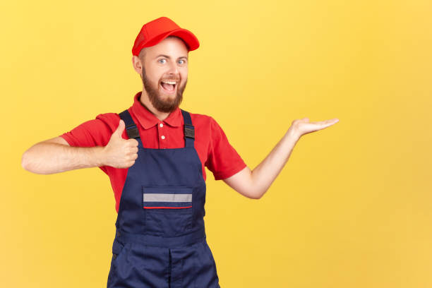 istock Handyman standing and presenting copy space for advertisement on his palm, showing thumb up. 1405670046