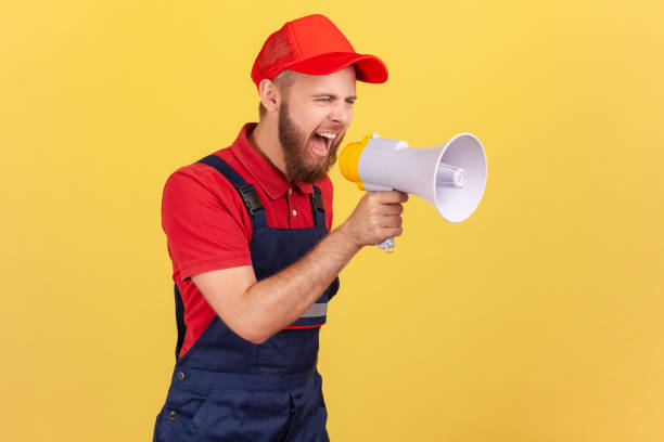istock Angry worker man holding megaphone near mouth loudly speaking, screaming, protesting. 1405670057