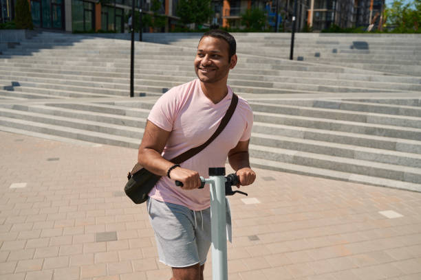 istock Male person with e-scooter standing on sidewalk 1405671126