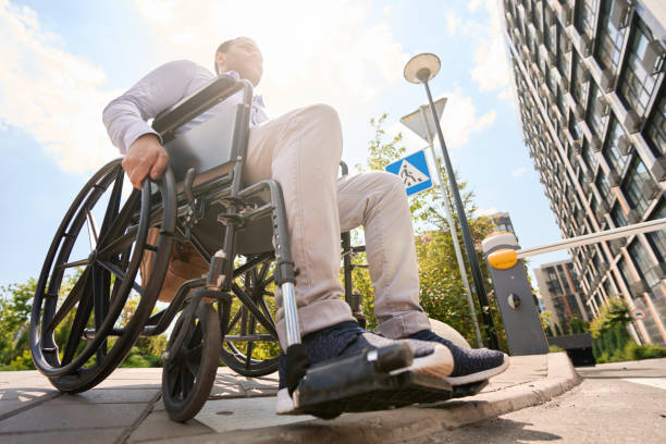 istock Wheelchair-bound young man is descending sidewalk curb 1405671309