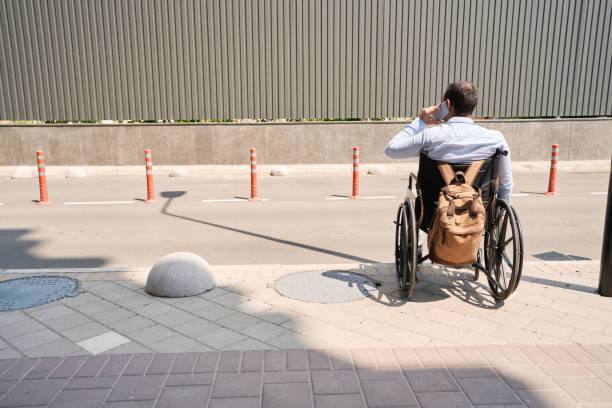 istock Wheelchair-bound man talking on mobile phone outside 1405671328