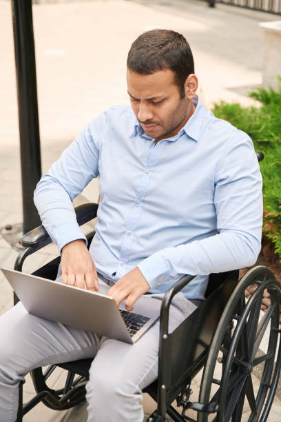 istock Handicapped man using his portable computer outdoors 1405671339