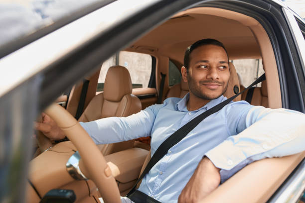 istock Pleased young man seated at steering wheel looking away 1405671425