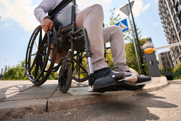 Disabled man going down curb in manual wheelchair Cropped photo of male sitting in wheel chair on edge of pavement paraplegic stock pictures, royalty-free photos & images