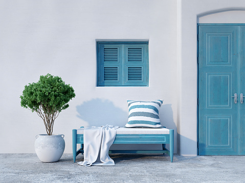May 29, 2019 - Mykonos, Greece. Traditional patio or dead end in narrow streets of Greek towns on Cyclades. Residential area, non-tourist view. Authentic design and architecture, worn-out whitewashed walls, blue doors and shutters, cobblestone pavement.