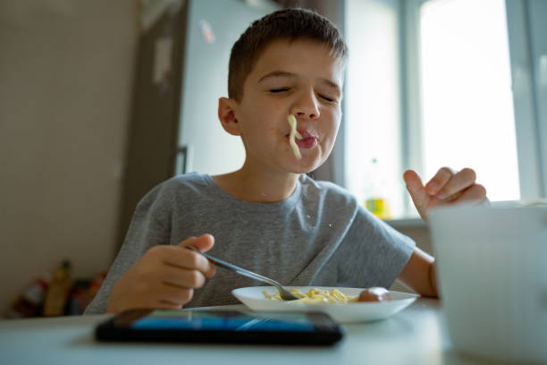 istock Cheerful, hungry boy eats pasta with appetite, retraction in pasta playfully 1405674617