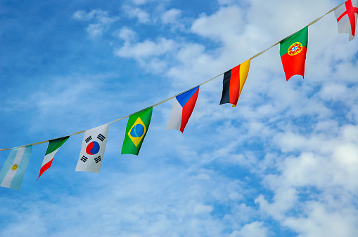 Colorful flags garland of different countries before blue sky