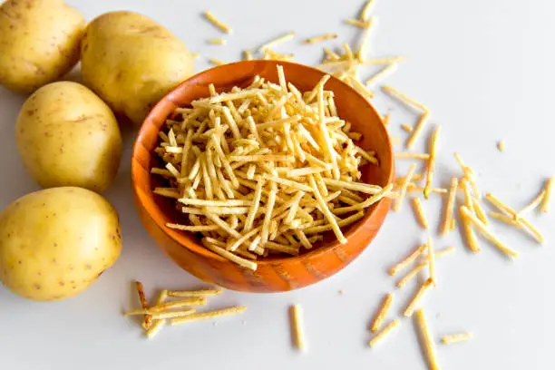 Photo of straw potato chips in a bowl on white background.