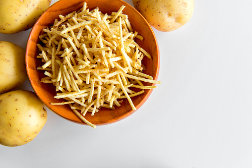 straw potato chips in bowl on white background.