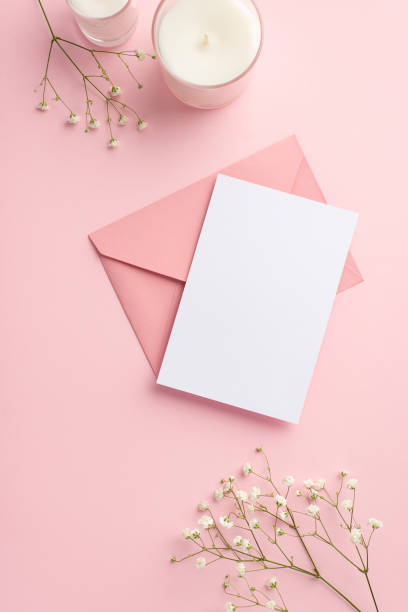 결혼식 초대장 개념. 빈 공간이있는 고립 된 파스텔 핑크 배경에 분홍색 봉투 엽서 양초와 흰색 집고 꽃의 상단보기 수직 사진 - greeting card envelope letter pink 뉴스 사진 이미지