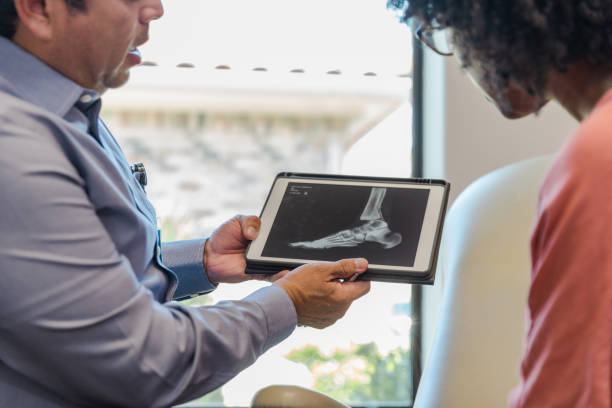 unrecognizable doctor uses digital tablet to show x-ray to woman - podiatrist podiatry orthopedic surgeon human foot imagens e fotografias de stock