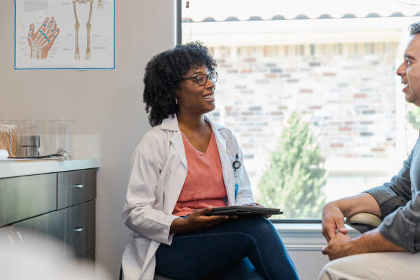 istock Female doctor smiles while chatting with male patient 1405683405