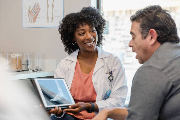 holding x-ray, female doctor listens to male patient - podiatrist podiatry orthopedic surgeon human foot imagens e fotografias de stock