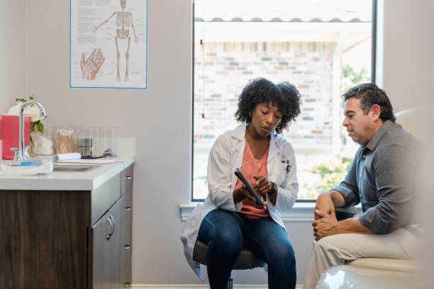 une femme médecin pointe quelque chose sur la tablette pendant que le patient écoute - cardiologue photos et images de collection