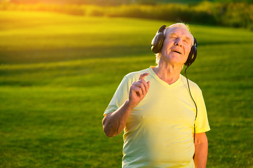 Senior male in headphones. Man with closed eyes outdoor. Favorite music in best quality. Power of art.