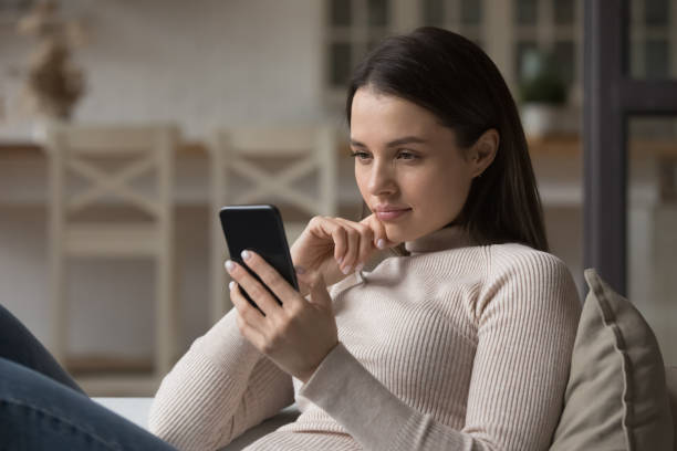 istock Focused millennial woman using mobile phone at home 1405688438
