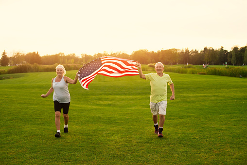 Couple with American flag. People jogging and smiling. Veterans of the sport. Victories and patriotism.